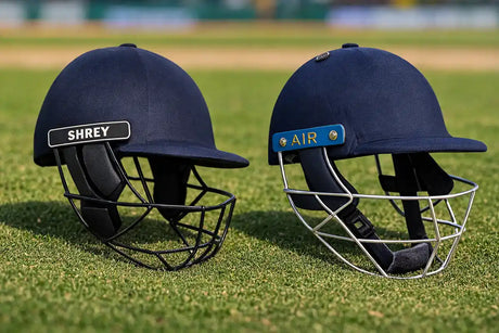 Two navy blue Shrey cricket helmets with protective face grills, showcasing different helmet styles for player safety and comfort