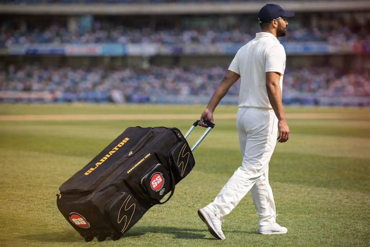 Cricketer pulling an SS Gladiator wheelie cricket bag across the field during tournament travel